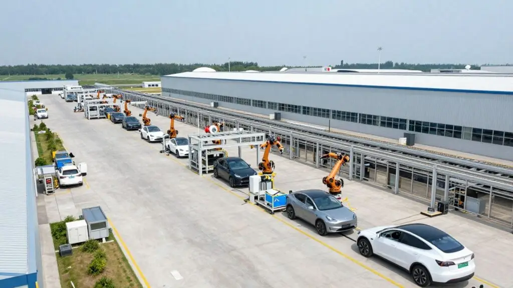Tesla factory assembly line with robotic arms and cars.